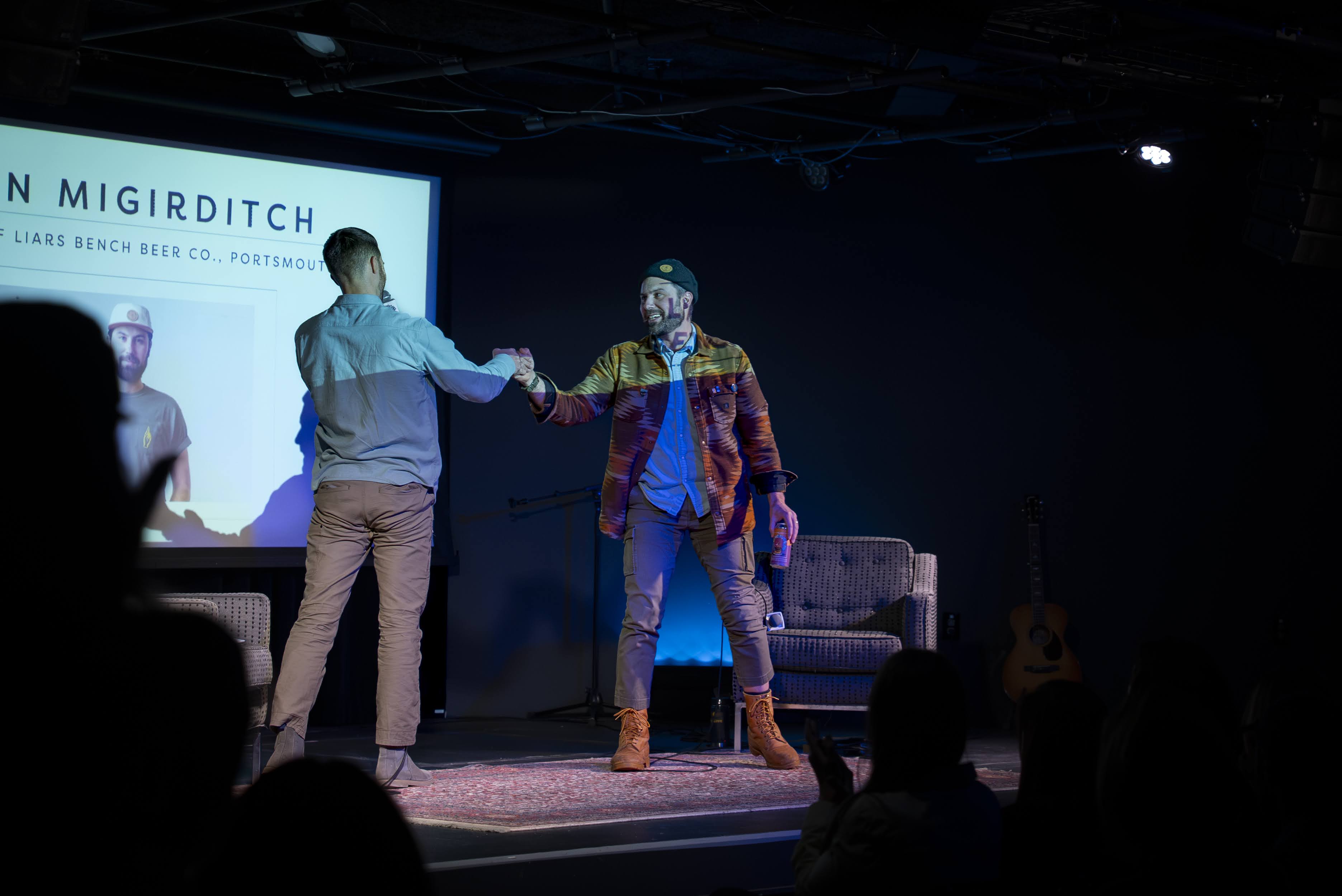 Troy Farkas and Dagan Migirditch fist-bumping on the Seacoast Stories live stage